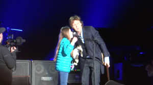 Dit meisje houdt een bord omhoog.. Dan roept Paul McCartney haar op het podium!