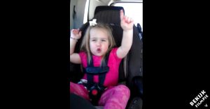Klein meisje zit in de auto in haar kinderzitje. Maar let op als de muziek begint!