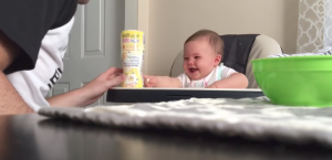 Baby zit klaar voor de lunch. En heeft daar de grootste lol in!