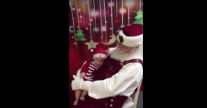Baby ligt op schoot van de Kerstman. Dan doet de man iets waardoor iedereen moet lachen