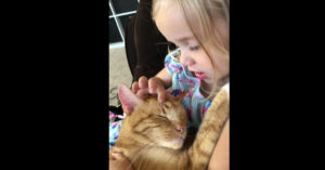Schattig meisje zingt voor haar kat die in haar armen ligt..
