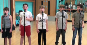 5 jonge kids staan klaar om te zingen voor hun repetitie..