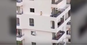 Angstaanjagend: kleine peuter huppelt over hoge richel van appartementencomplex